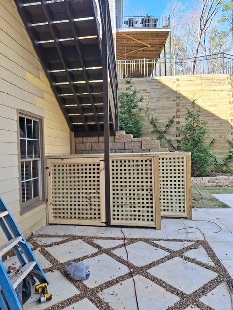 Wooden lattice fence panels in a backyard patio area with pergola overhead and brick retaining wall